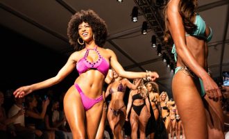Una mujer en bikini camina con confianza por la pasarela durante PARAISO Miami Swim Week.