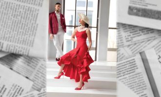 Un hombre y una mujer con vestidos rojos posando juntos en un entorno elegante y vibrante.