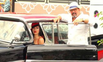 Un hombre y una mujer con sombrero rojo y vestido blanco sentados en un automóvil clásico en la Calle 8.