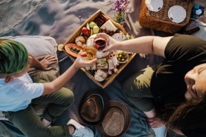 People clinking glasses above a tray full of snacks.