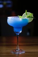 A fresh blueberry margarita with mint leaves and a lemon wedge on the edge.
